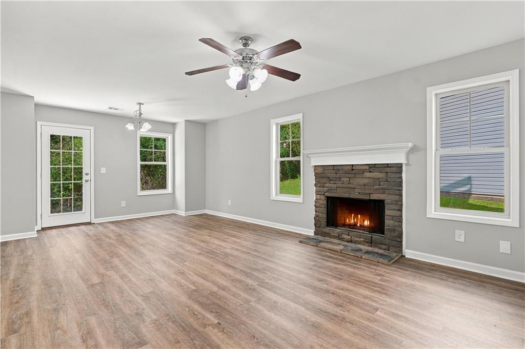 Living room with stacked stone wood-burning fireplace and new flooring