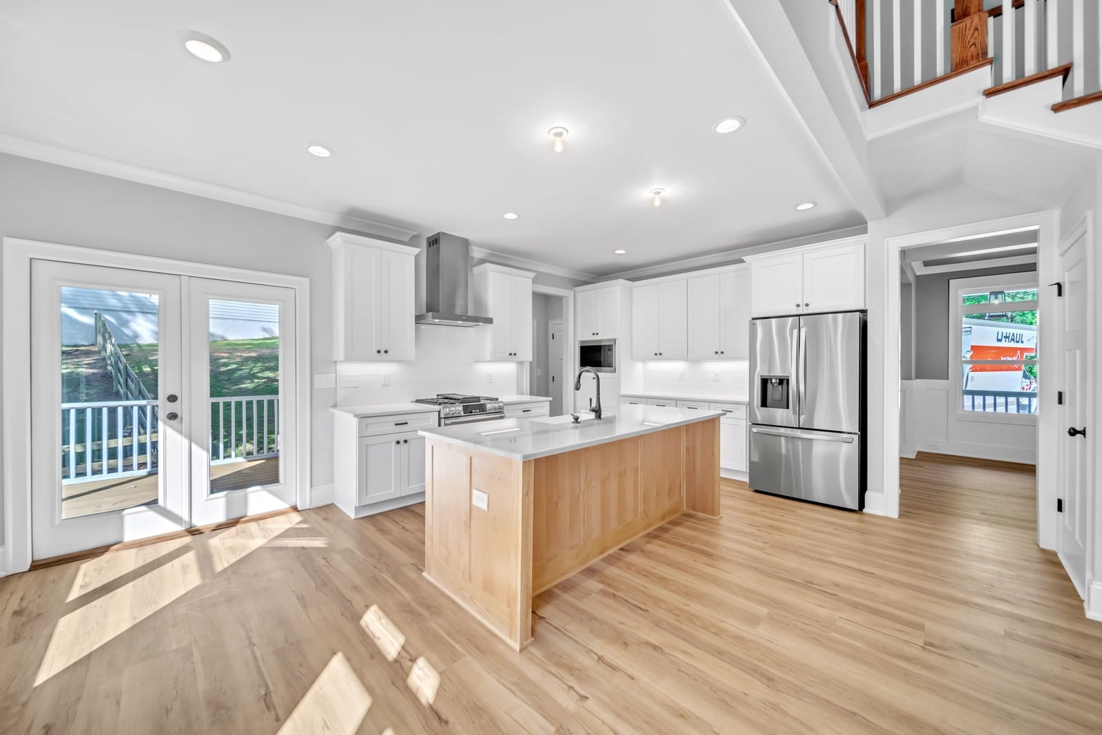 White shaker kitchen with natural maple island and French doors